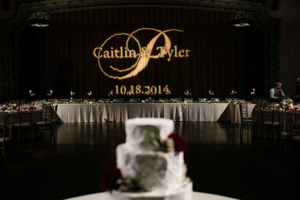 A wedding cake is shown in front of the bride and groom.